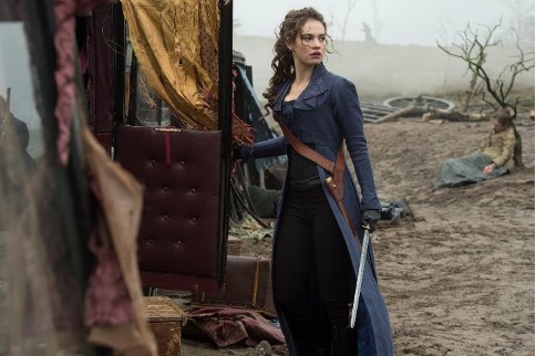 Lilly James as Elizabeth Bennet standing next to a vehicle at Frensham Little Pond during a zombie battle scene
